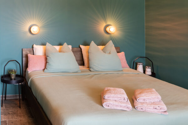 Foto van een tweepersoonsbed in roze en lichtgroene tinten